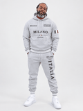 Men's Fall Winter 2026 hoodie and jogger set in heather-gray polyester, with Milano Italia lettering and Italian flag accents.
