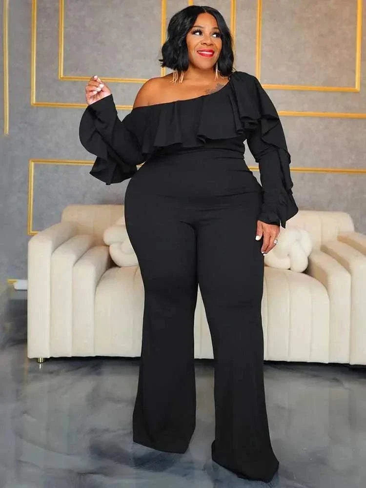 Elegant Woman Jumpsuit in black fabric, featuring an off-shoulder ruffled neckline, long sleeves and a wide-leg silhouette.